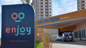 Naamplaatje voor 'enjoy Hotels & Resorts' en 'Solar das Águas Park Resort', met een parkeerplaats en voertuigen ervoor.