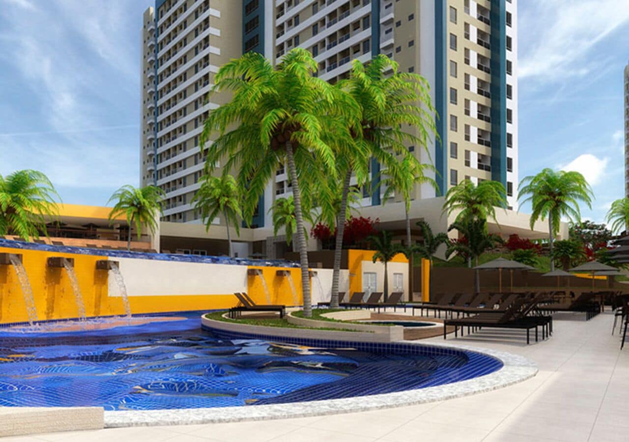 Una piscina con diseño azul de mosaicos, rodeada de palmeras y sillones de descanso.