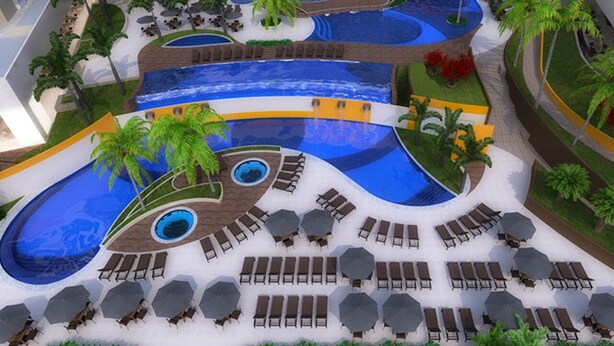 Een zwembadcomplex met meerdere niveaus, diverse waterattracties, ligbedden en palmbomen.