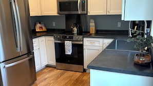 A modern kitchen with stainless steel appliances, white cabinetry, and a wooden floor. - The Central Ranch— minutes to Acadia & Coastal Maine (Ellsworth)