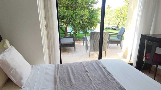 A hotel room with a bed, a view of the outdoor patio, and a table with chairs. - Villa Eden L'Orangeraie Dyar Shemsi Agadir (Taroudant)