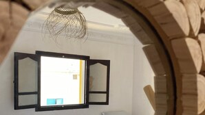 A bedroom with two beds, a window, and a mirror reflecting the room. - TITRYTE SURF HOUSE (Agadir)