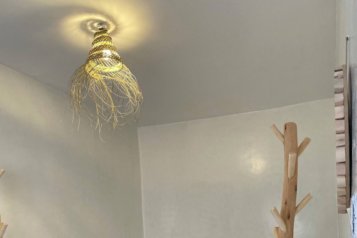 A bedroom with two beds, a hanging light fixture, and a wooden tree-like structure.
