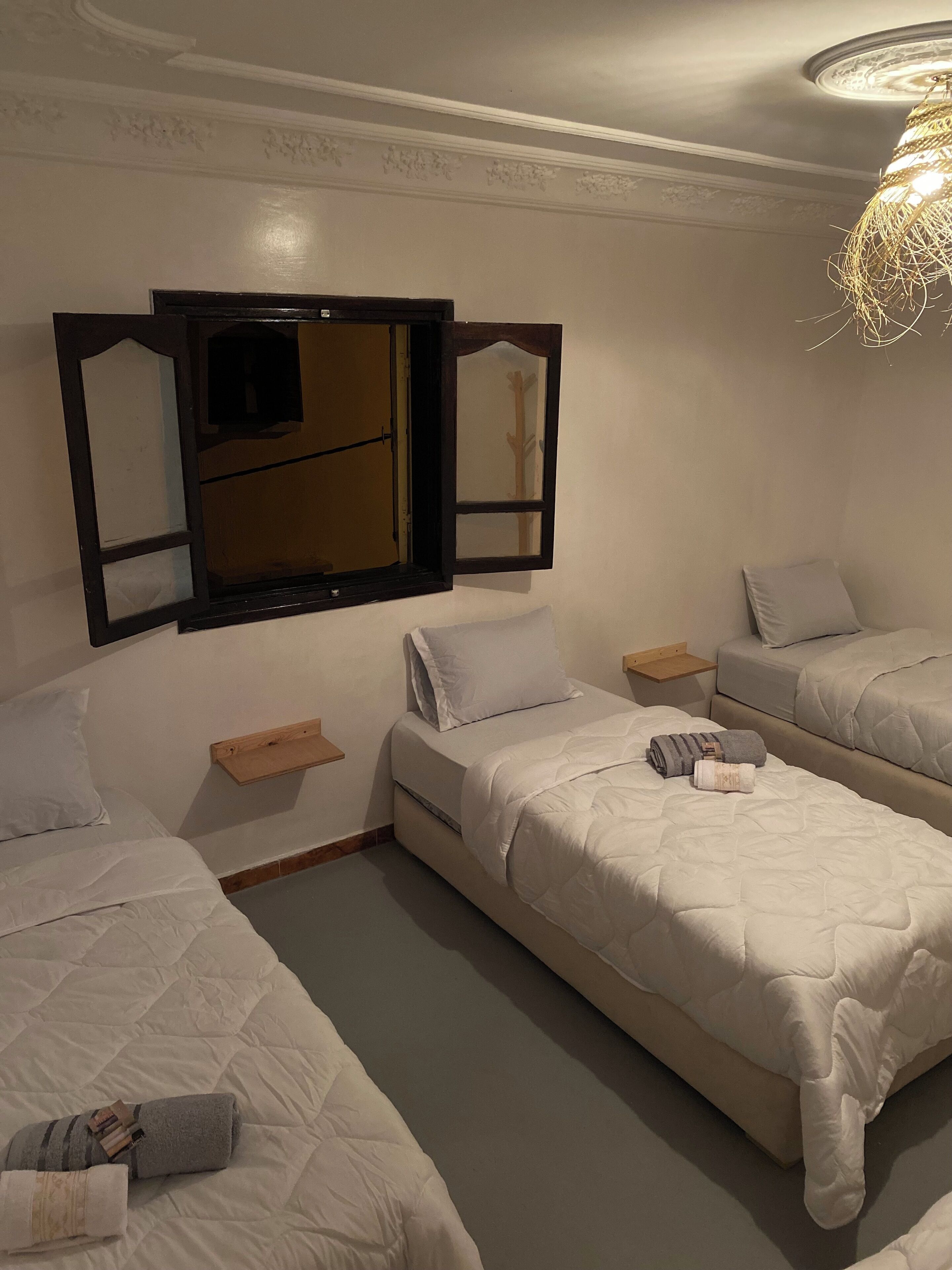 Une chambre d’hôtel avec deux lits, un grand miroir et un luminaire suspendu.