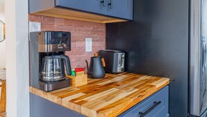 Eine Küche mit Kaffeemaschine, Toaster und Wasserkocher auf einer Holzausziehtisch.