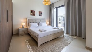 Ein modernes Schlafzimmer mit einem großen Bett, Nachttischlampen, einem gemusterten Teppich und Blick durch ein großes Fenster.