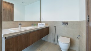 Ein modernes Badezimmer mit einem Holzbadezimmermöbel, zwei Waschbecken, einem großen Spiegel, einer Toilette und einer Dusche.