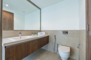 A modern bathroom with a wooden vanity, two sinks, a large mirror, a toilet, and a shower. - Tilal Al Ghaf B329 in Dubai (Dubai)