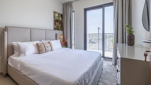 Ein modernes Hotelzimmer mit einem großen Bett, einem Balkon mit Blick und einem Schreibtisch. An der Wand hängt ein Gemälde.