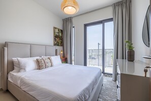 A modern hotel room with a large bed, a balcony with a view, a dresser, and a painting on the wall. - Tilal Al Ghaf B329 in Dubai (Dubai)