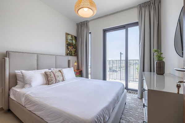 A modern hotel room with a large bed, a balcony with a view, a dresser, and a painting on the wall. - Tilal Al Ghaf B329 in Dubai (Dubai)