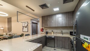 A modern kitchen with a large island, built-in appliances, and a dining area with a sofa and table. - MBL Residence 1205 jlt (Dubai)