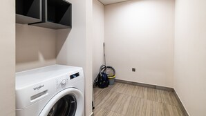 A laundry room with a Whirlpool washer and dryer, a vacuum cleaner, and a mop. - MBL Residence 1205 jlt (Dubai)