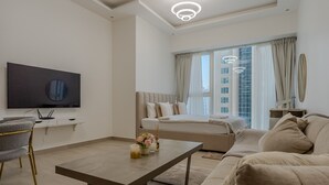A modern living room with a flat-screen TV, a sofa, a coffee table, and a bed with a view of the cityscape. - Me Do Re JLT 1408 in Dubai (Dubai)
