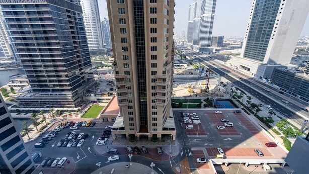 A high-rise building with a central courtyard, multiple parking levels, and surrounding urban infrastructure. - Me Do Re JLT 1408 in Dubai (Dubai)