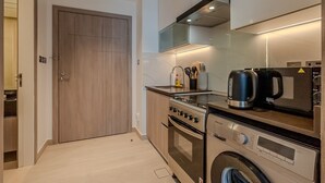 A modern kitchen with a built-in oven, microwave, and washing machine. - Me Do Re JLT 1408 in Dubai (Dubai)