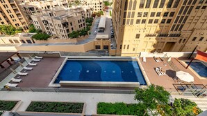 Una piscina en la azotea con sillones reclinables y vistas de edificios altos.