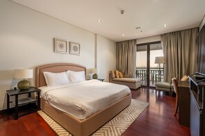 A hotel room with a large bed, a sofa, a chair, a desk, and a balcony with curtains. - Anantara South 309 in Dubai (Dubai)