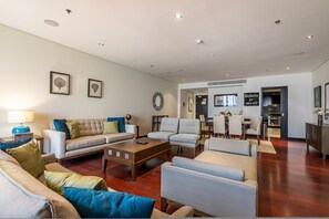 A spacious living room with a sofa, armchairs, a coffee table, and a dining area with chairs and a table. - Anantara South 309 in Dubai (Dubai)