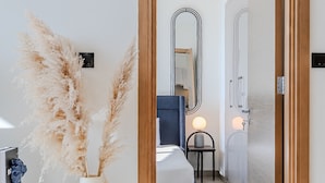 A modern hotel room with a wooden door, a bedside table with a lamp, a bed, and a wall-mounted mirror. - Sobha Waves 2915 in Dubai (Dubai)