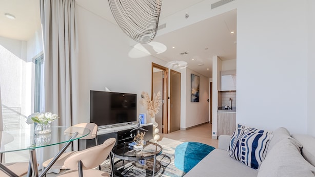 A modern living room with a glass coffee table, beige sofa, and a flat-screen TV. - Sobha Waves 2915 in Dubai (Dubai)