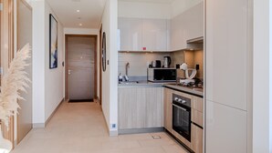 A modern kitchen with wooden cabinets, a microwave, stove, and a sink. - Sobha Waves 2915 in Dubai (Dubai)