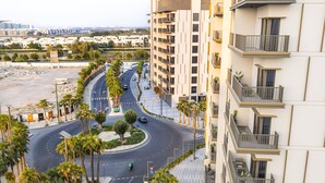 A multi-story residential building with balconies, a curved road, and palm trees. - MAG Building 920 711 (Dubai)