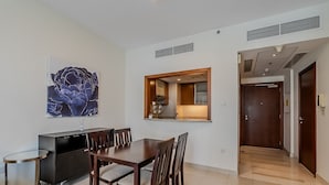 A dining area with a wooden table and chairs, a small round table, a cabinet, and a large abstract painting on the wall. - Standpoint 706 in Dubai (Dubai)