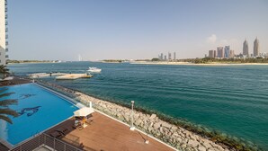 A poolside view with a clear view of the sea and city skyline. - Azure Residences 117 Premium 2bdr Palm (Dubai)