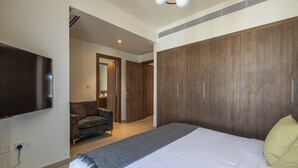 A modern bedroom with a large bed, a flat-screen TV, a wardrobe, and a seating area with a sofa. - Tilal AL Ghaf 245 in Dubai (Dubai)