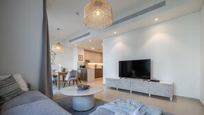 A modern living room with a sofa, a coffee table, and a TV on a cabinet. There is a dining area in the background with a table and chairs. - Tilal AL Ghaf 245 in Dubai (Dubai)