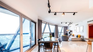 Amplia sala de estar con una gran mesa de comedor, iluminación moderna y ventanas amplias que ofrecen vistas a la ciudad.