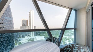 Una habitación moderna con un amplio ventanal que ofrece vista a la ciudad, una mesa redonda y cojines estampados.