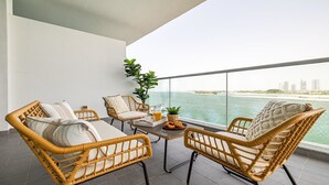 Een balkon met rieten meubilair, een tafel met dienblad en een potplant.