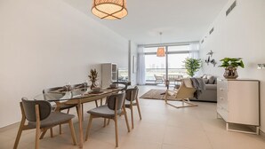 Een moderne woonkamer met een eetgedeelte, grote ramen en uitzicht op de stad.