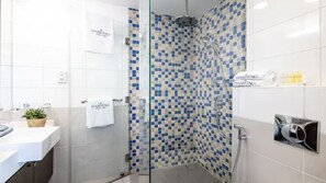 A modern bathroom with a glass shower enclosure, white tiles, and a hashtag towel. - Azure Residences 317 Luxury 2bdr Palm (Dubai)