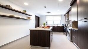 Een moderne keuken met donkerhouten kasten, een centraal eiland en inbouwplanken.