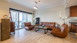 A spacious living area with a large window, leather sofas, a coffee table, and a view of the city. - Lake View Residence 208 (Dubai)