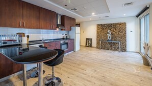 A modern kitchen with wooden cabinets, a black countertop, and a built-in oven. - Lake View Residence 208 (Dubai)
