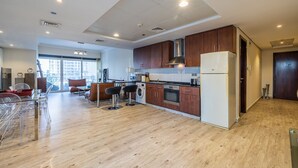 A modern kitchen with wooden cabinets, a stainless steel range hood, and a built-in oven. There is a washing machine and a refrigerator in the adjacent area. - Lake View Residence 208 (Dubai)
