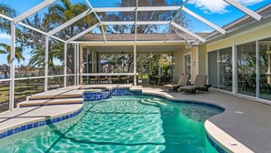 A pool area with a glass enclosure, a hot tub, and outdoor seating.