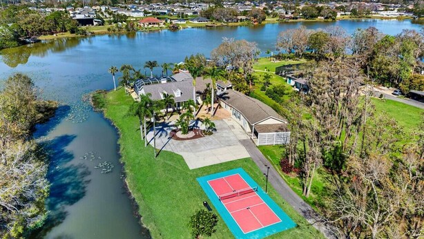 A residential property with a tennis court, a swimming pool, and a large house with a garage.