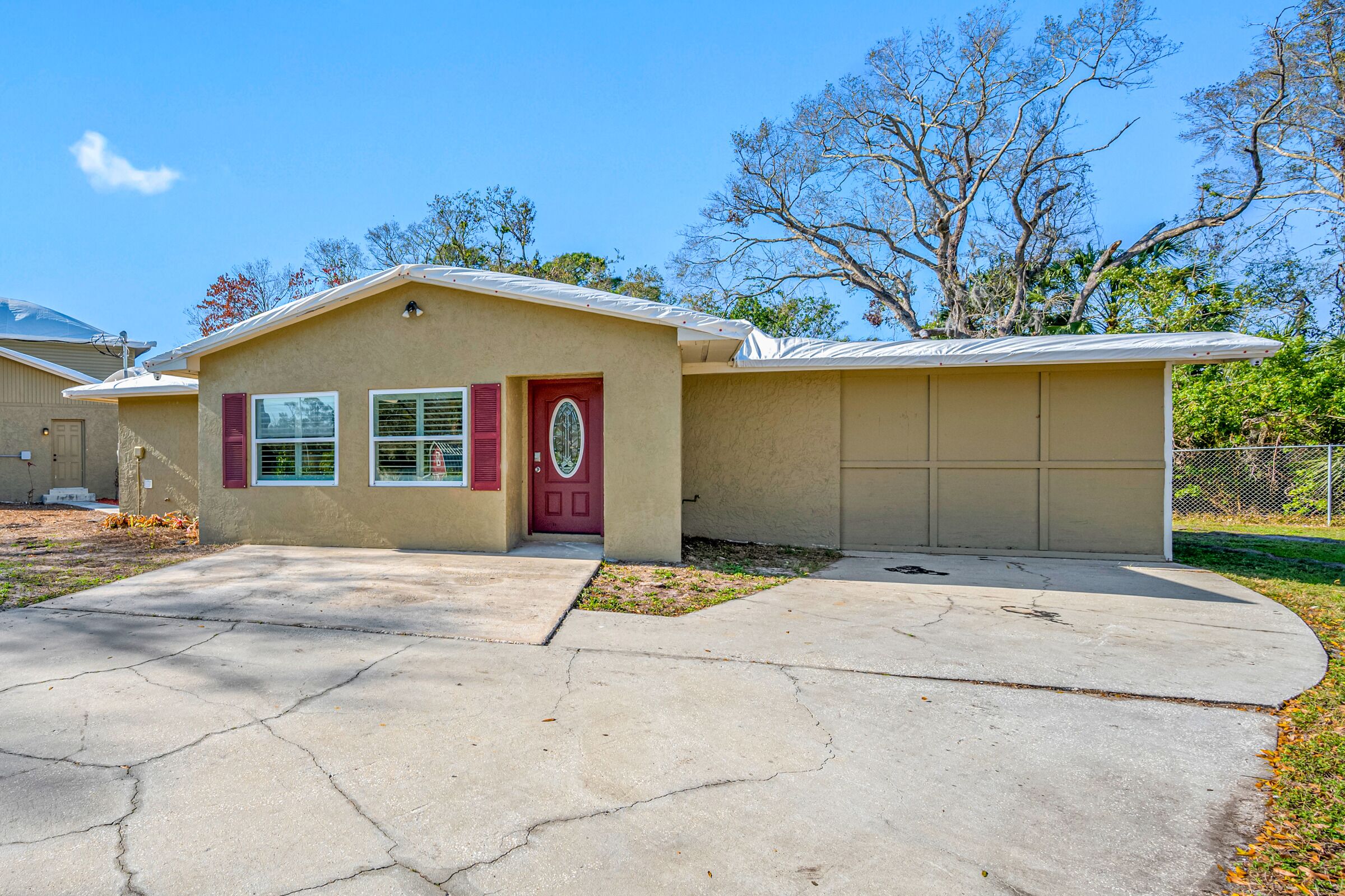 A single-story house with a garage, a front door with a red doorbell, and a small front yard.