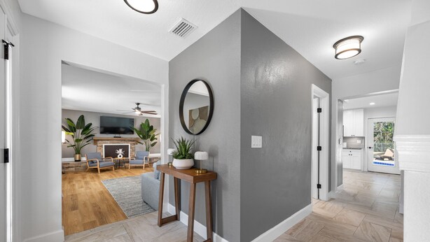 A modern interior with a herringbone floor pattern, a grey accent wall, and a wooden console table with plants. - The Perfect Family Retreat w Pool and Games (Tampa)