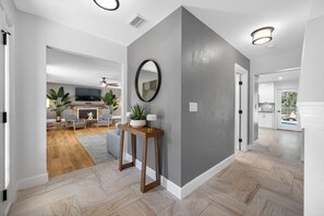 A modern interior with a herringbone floor pattern, a grey accent wall, and a wooden console table with plants. - The Perfect Family Retreat w Pool and Games (Tampa)