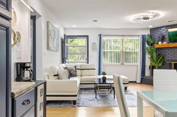 A modern living room with a sofa, coffee table, and a TV mounted on a brick wall.