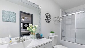 Une salle de bain avec un lavabo blanc, des toilettes et un espace douche.