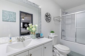 A bathroom with a white sink, a toilet, and a shower area.