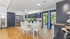 Une cuisine moderne avec un coin repas, comprenant un grand îlot central, des appareils électroménagers intégrés et une vue sur l’extérieur.