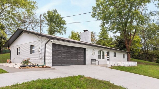 Une maison de plain-pied avec un garage, un porche à l’avant et un petit jardin.